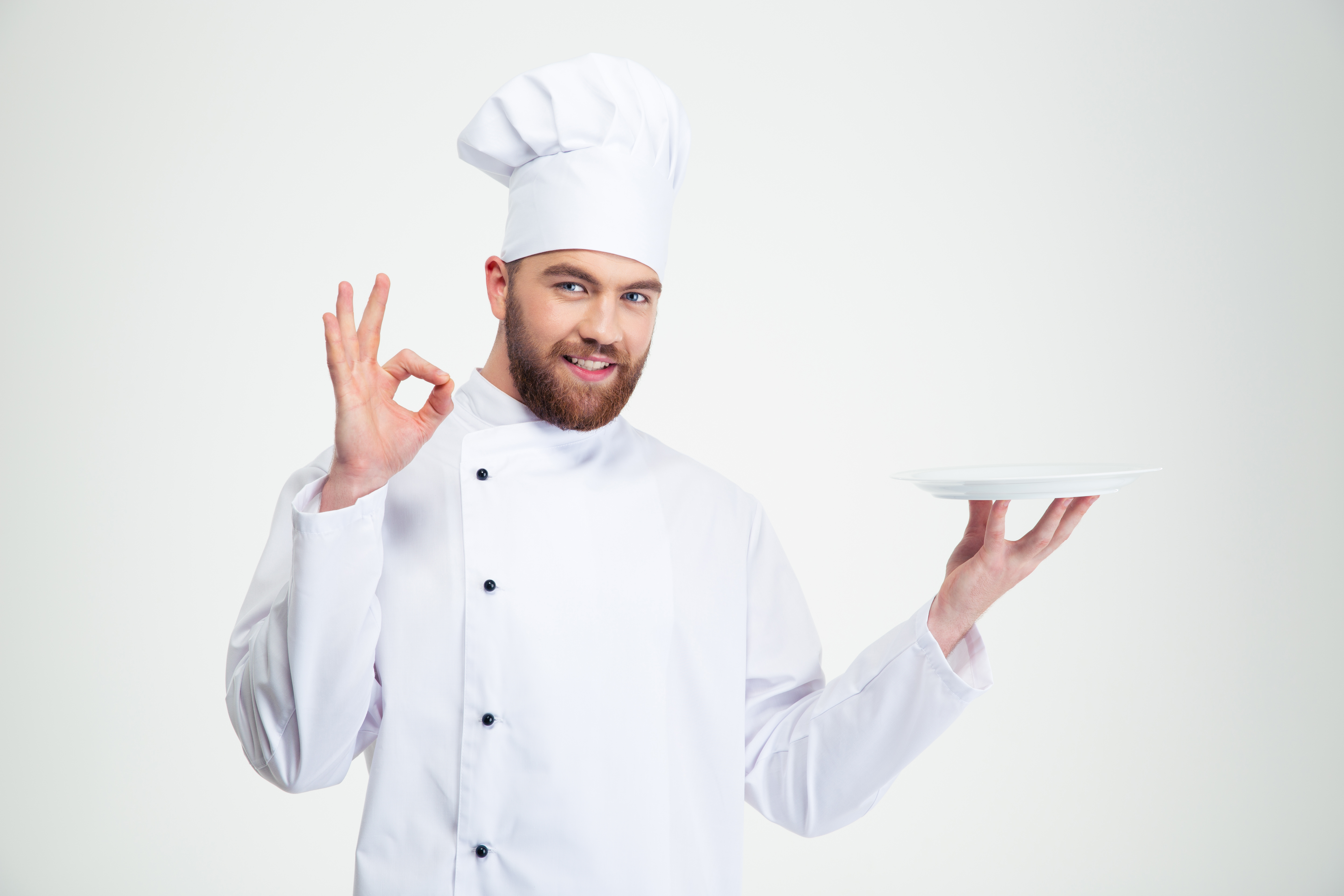 Portrait of a man chef showing ok sign and empty plate isolated on a w